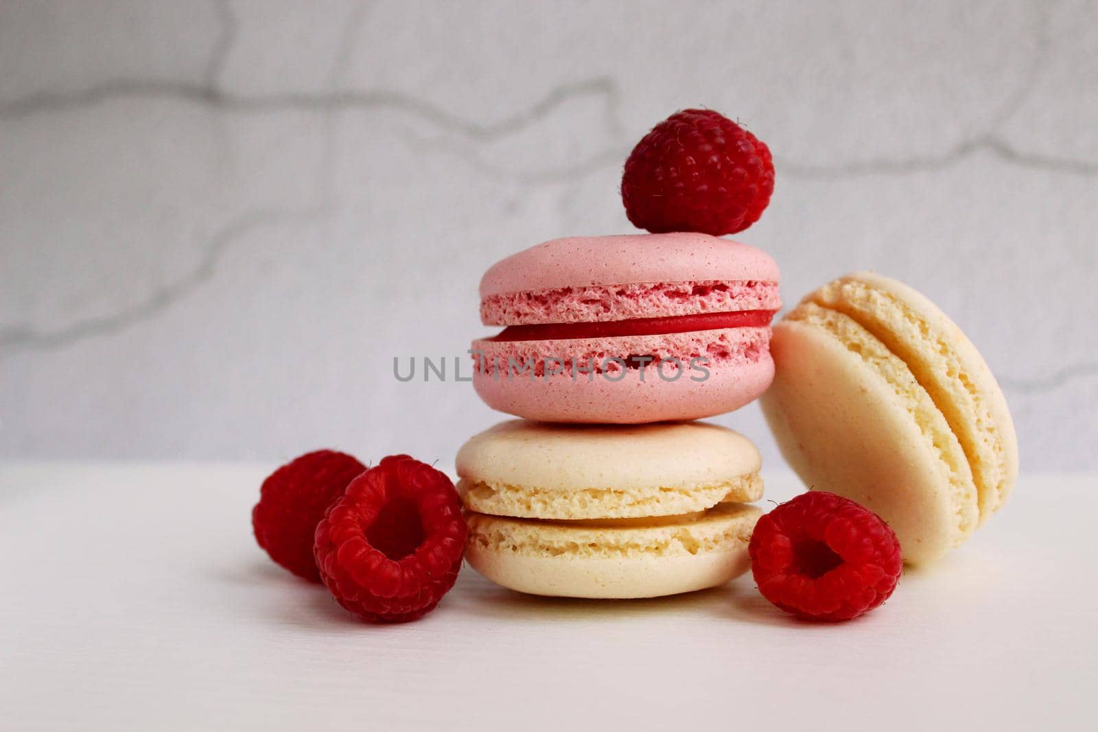 White and pink macaroon cakes with raspberries on an abstract gray background. Sweet food. Nice design for any purpose. Desktop wallpaper. Photo for the calendar.