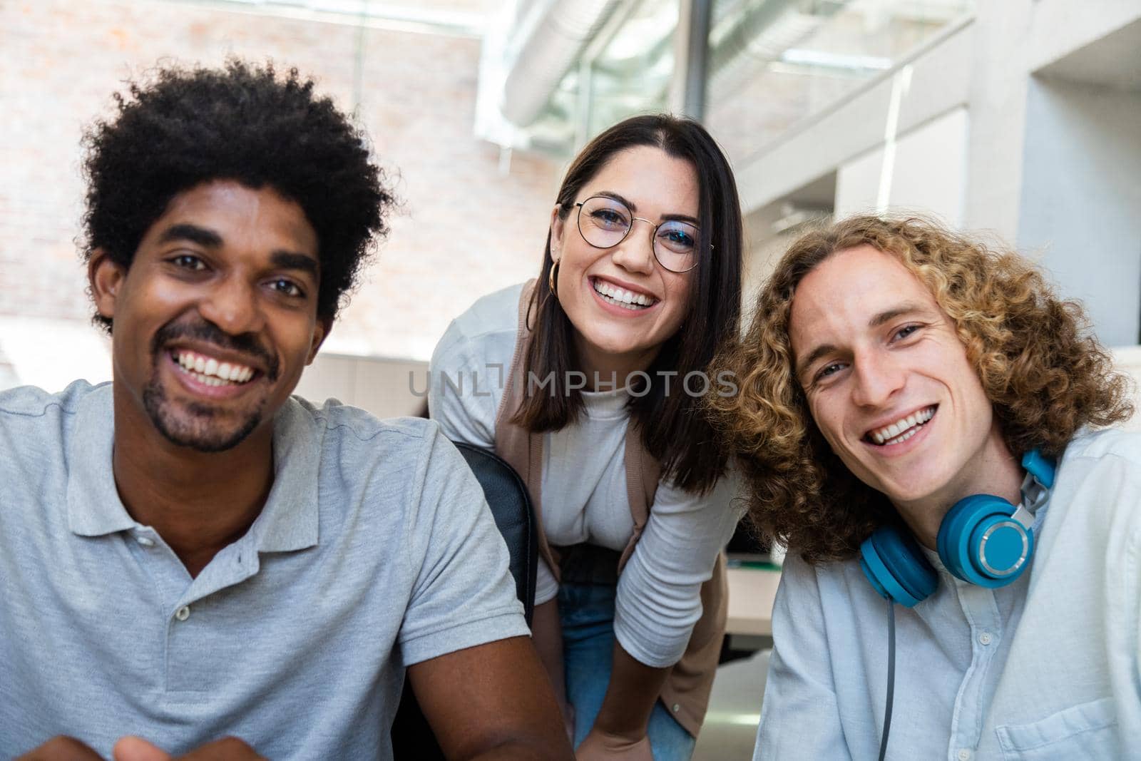Smiling young multiracial team of coworkers looking at camera in the office. Teamwork concept.