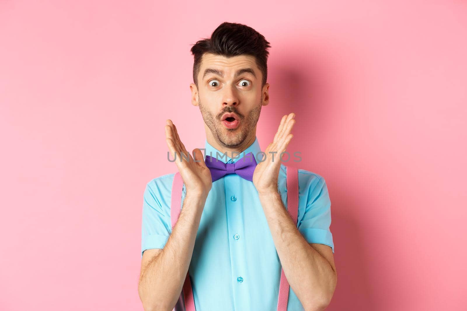 Portrait of funny guy say wow, staring amazed at camera, checking out awesome offer, standing in classy bow-tie on pink background by Benzoix