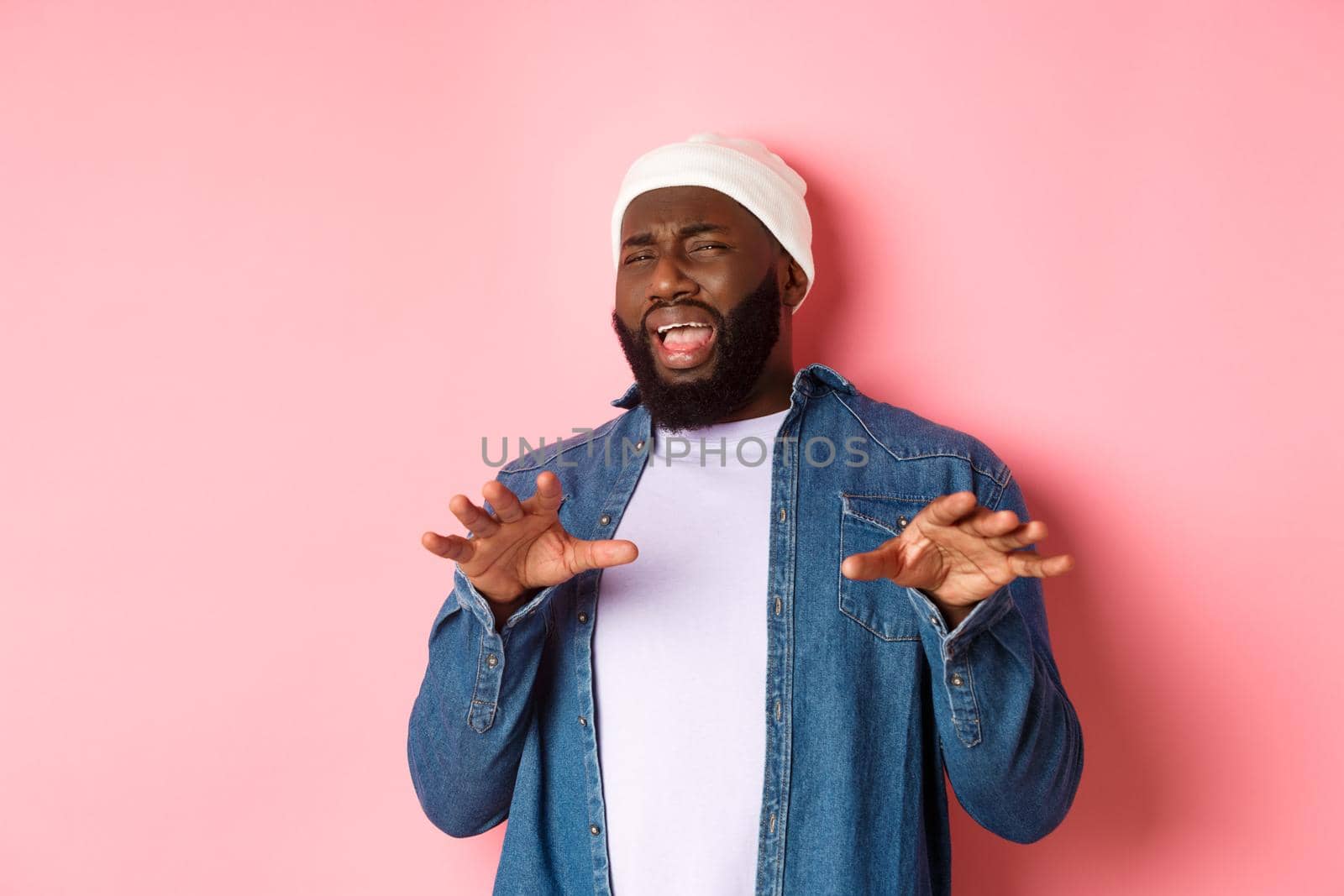 Image of disgusted picky Black man cringe from something disturbing, refusing bad offer, grimacing with dislike and aversion, standing over pink background.