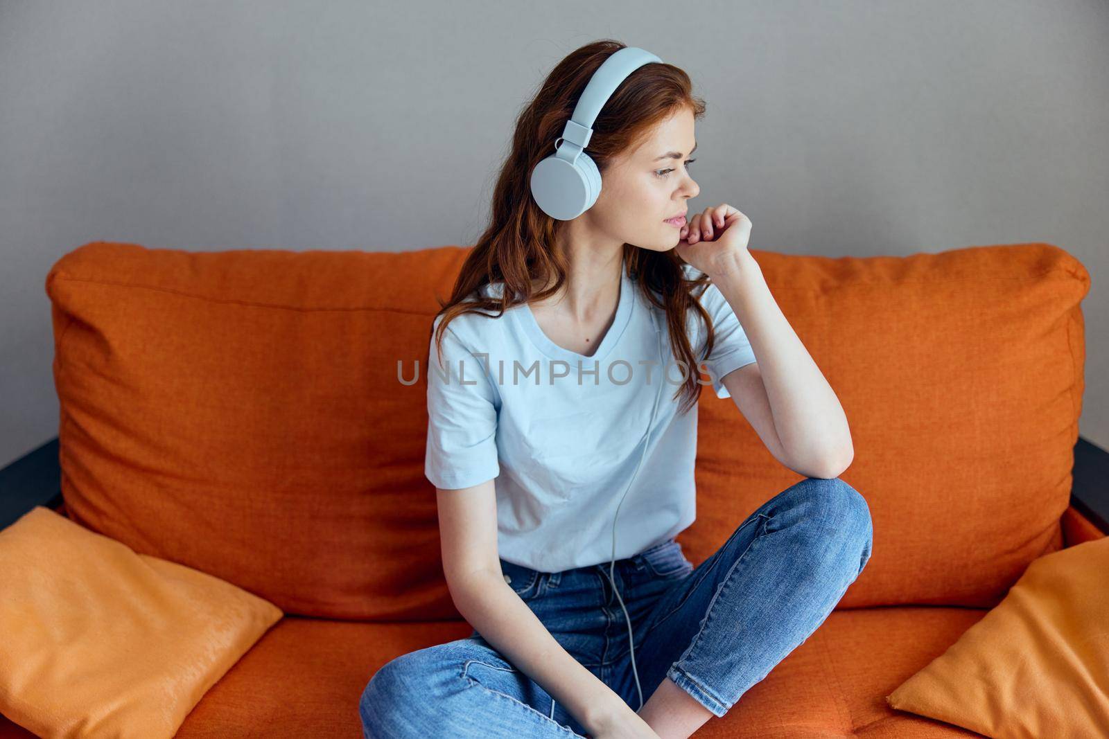 woman sitting on the couch at home listening to music on headphones apartments. High quality photo