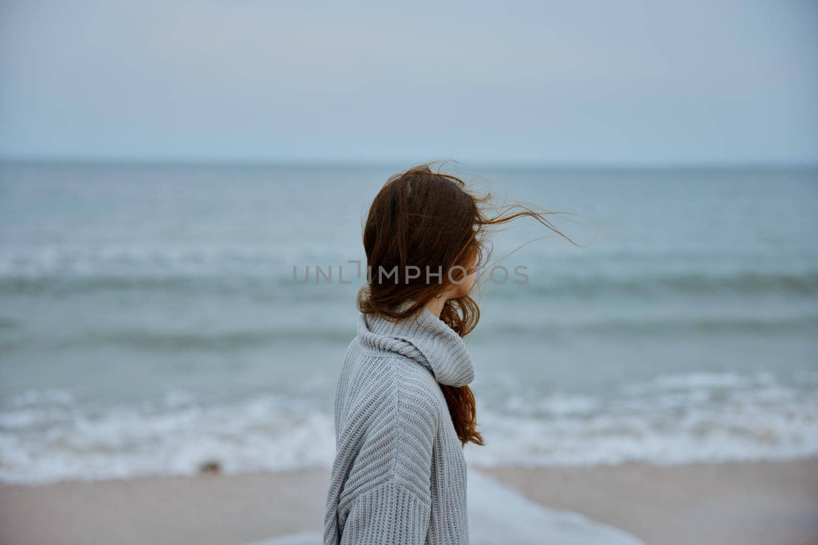 woman red hair in a sweater by the ocean unaltered. High quality photo