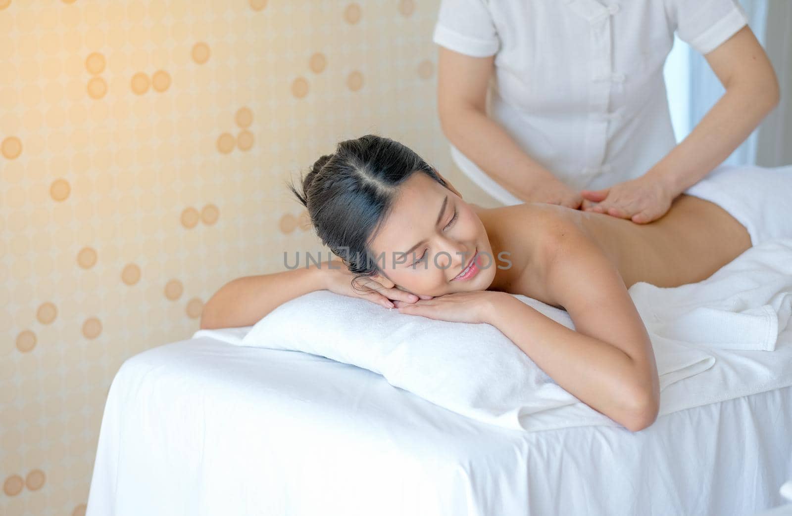 Portrait of Asian beautiful woman lie on bed and get the spa massage in the room with day light.