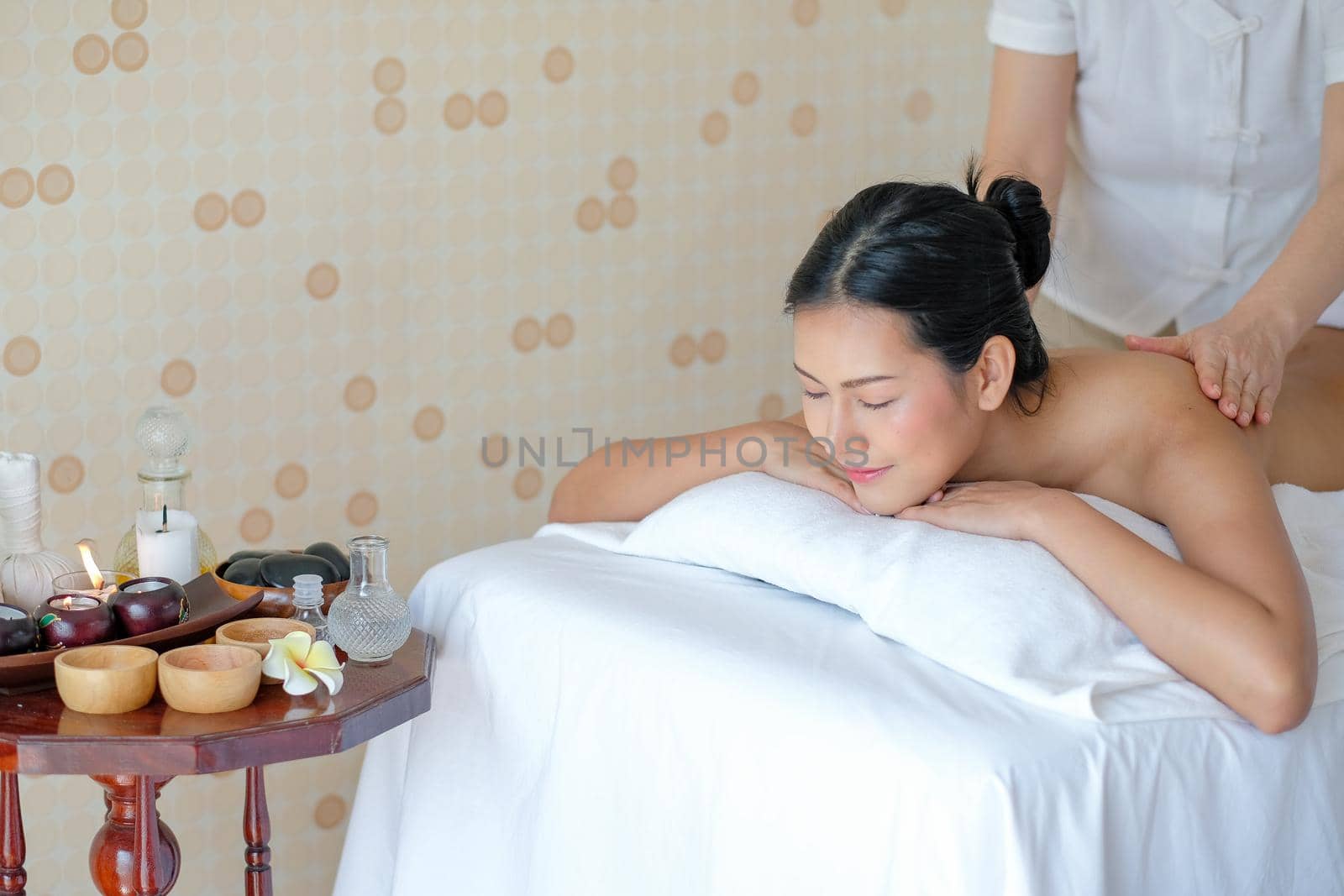 Asian beautiful girl close her eyes and lie on bed and enjoy the spa massage in the room with day light.