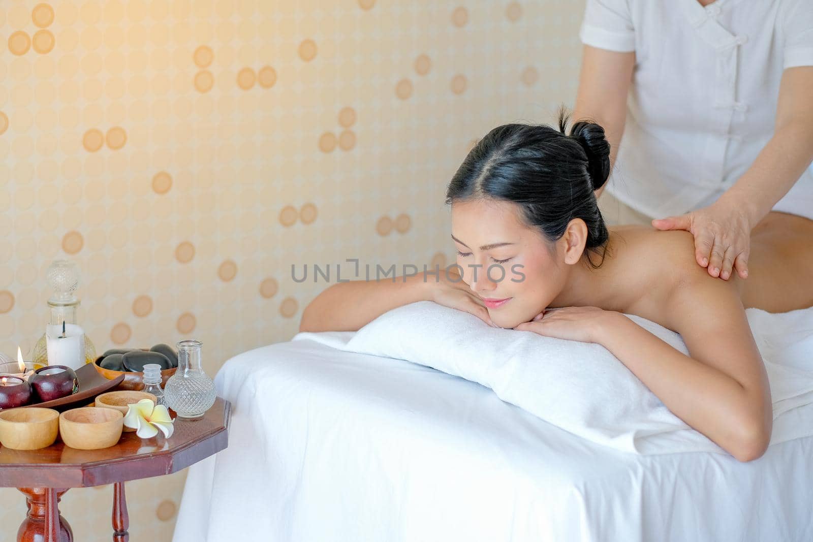 Portrait of Asian beautiful woman lie on bed and get the spa massage in the room with day light.