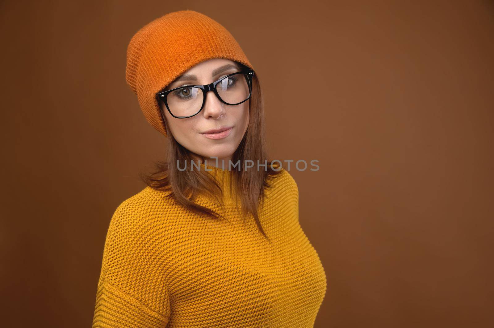 Attractive middle-aged Caucasian woman wearing a yellow sweater hat and glasses looks at camera. Vision problem and people wearing glasses by yanik88