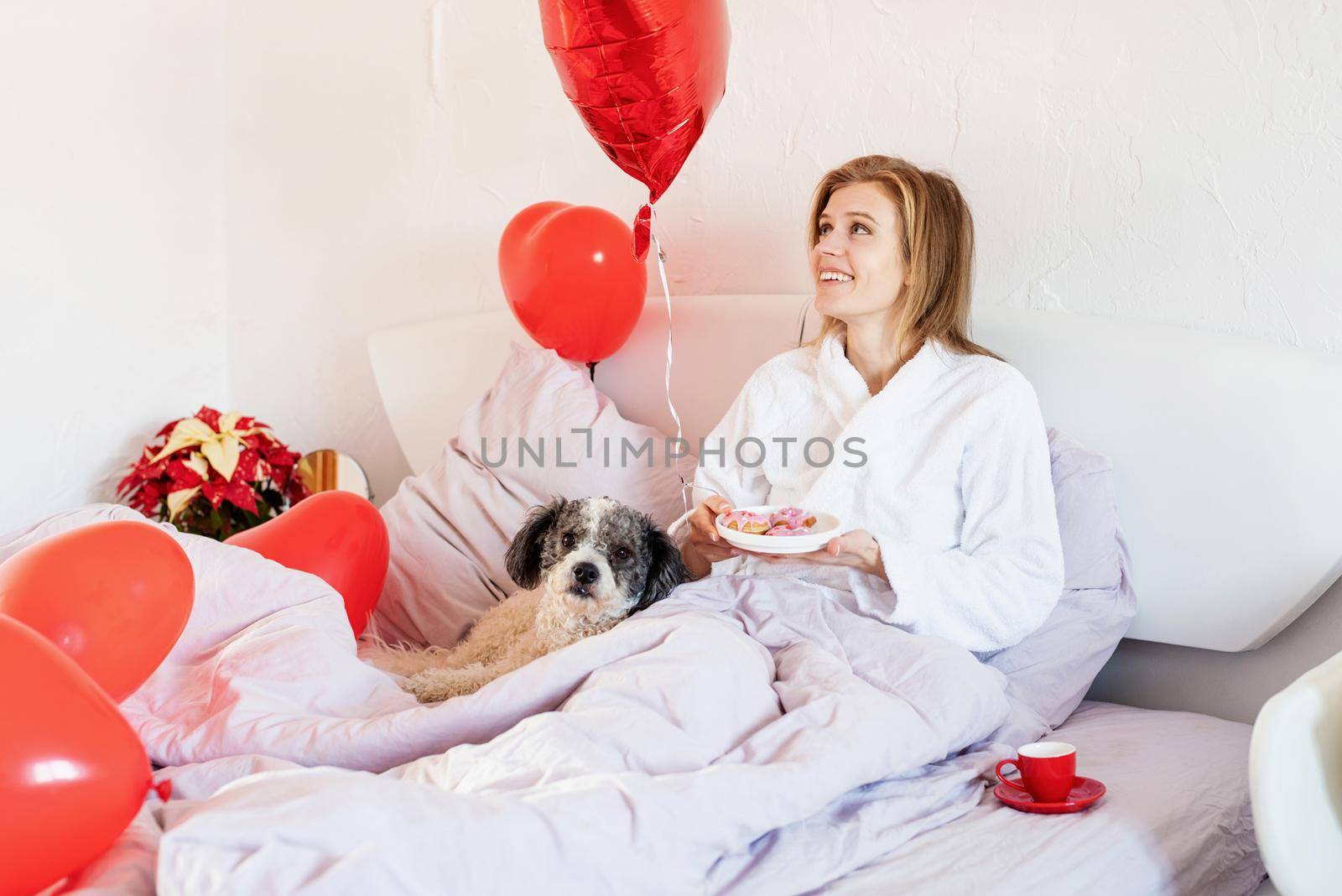 Happy valentines day. young woman lying on the bed and looking at red balloon