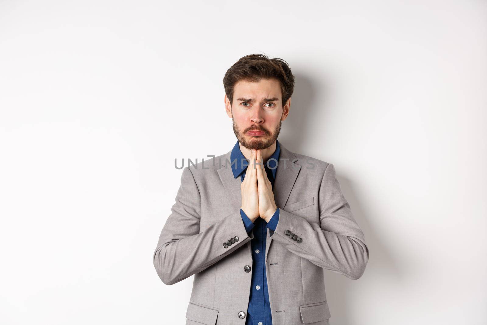 Miserable whining businessman asking for loan, need help and begging you, sobbing and say please with sad face, standing on white background, ask for forgiveness.