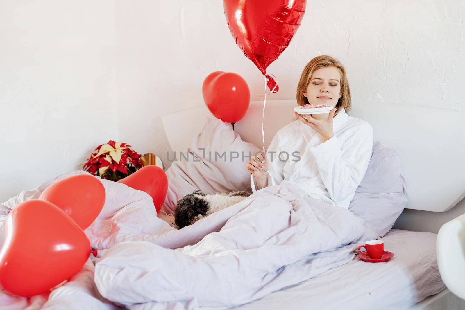 Happy valentines day. young woman lying on the bed and looking at red balloon