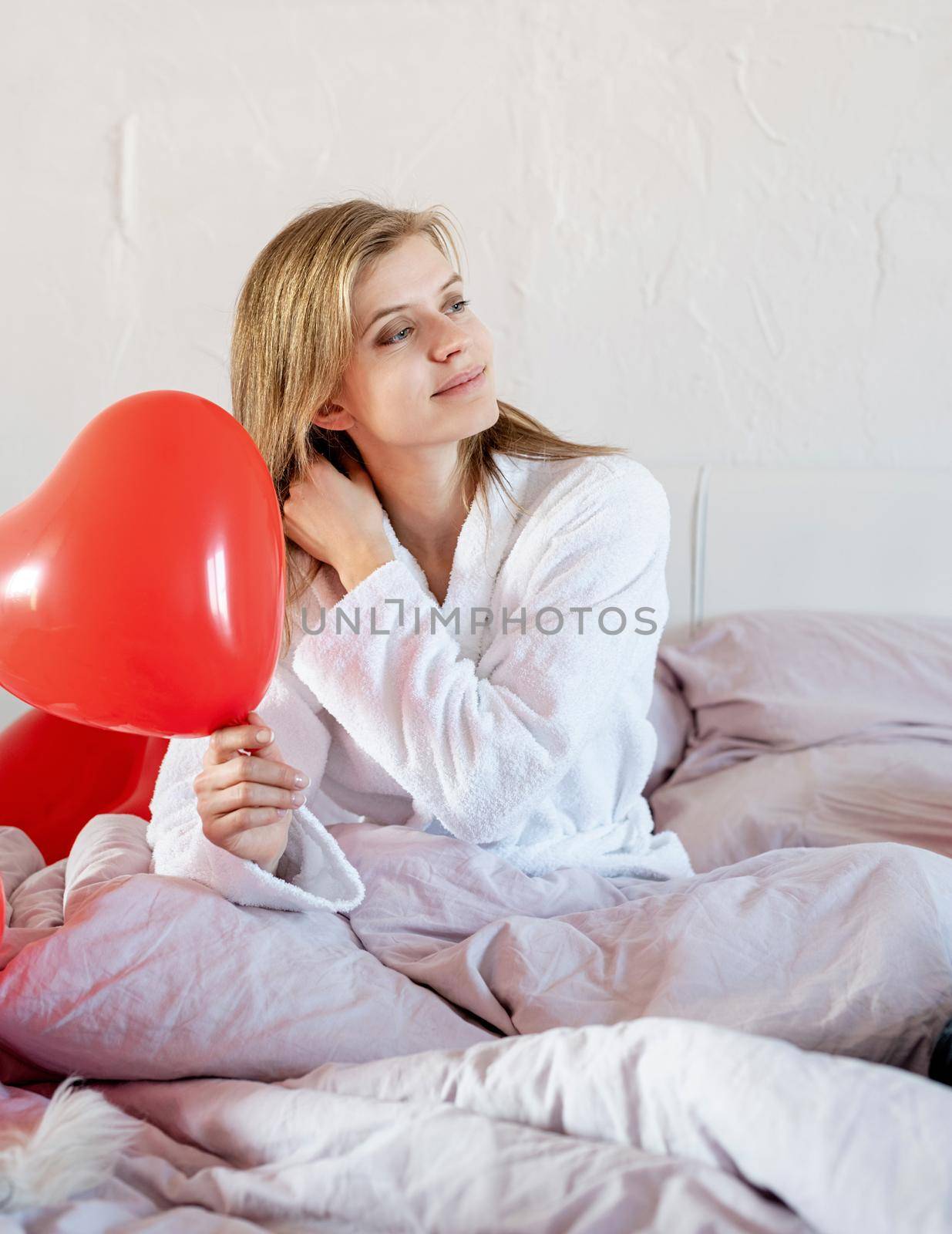 young woman lying on the bed and looking atred balloon by Desperada