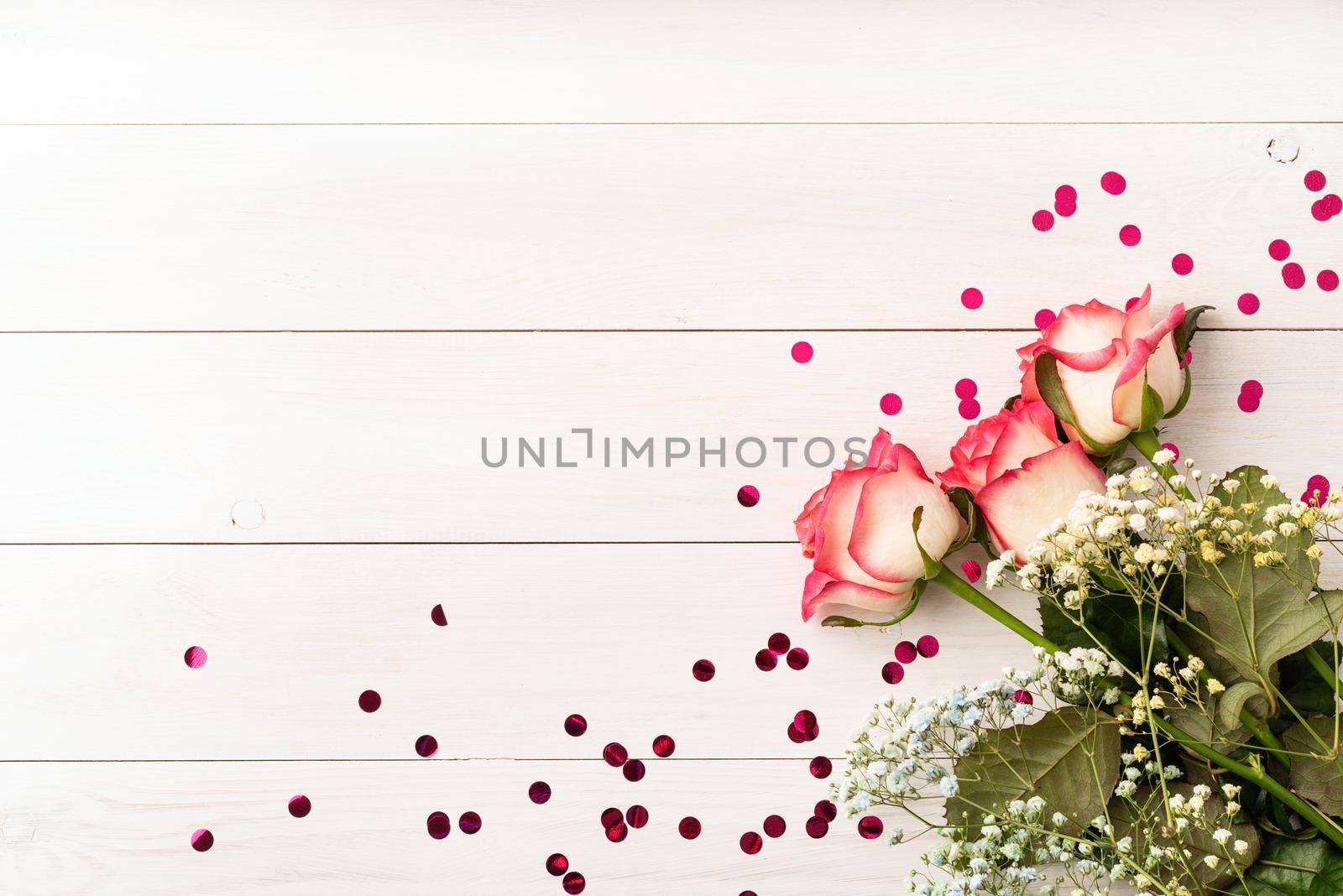 Pink roses with confetti on white wooden background by Desperada