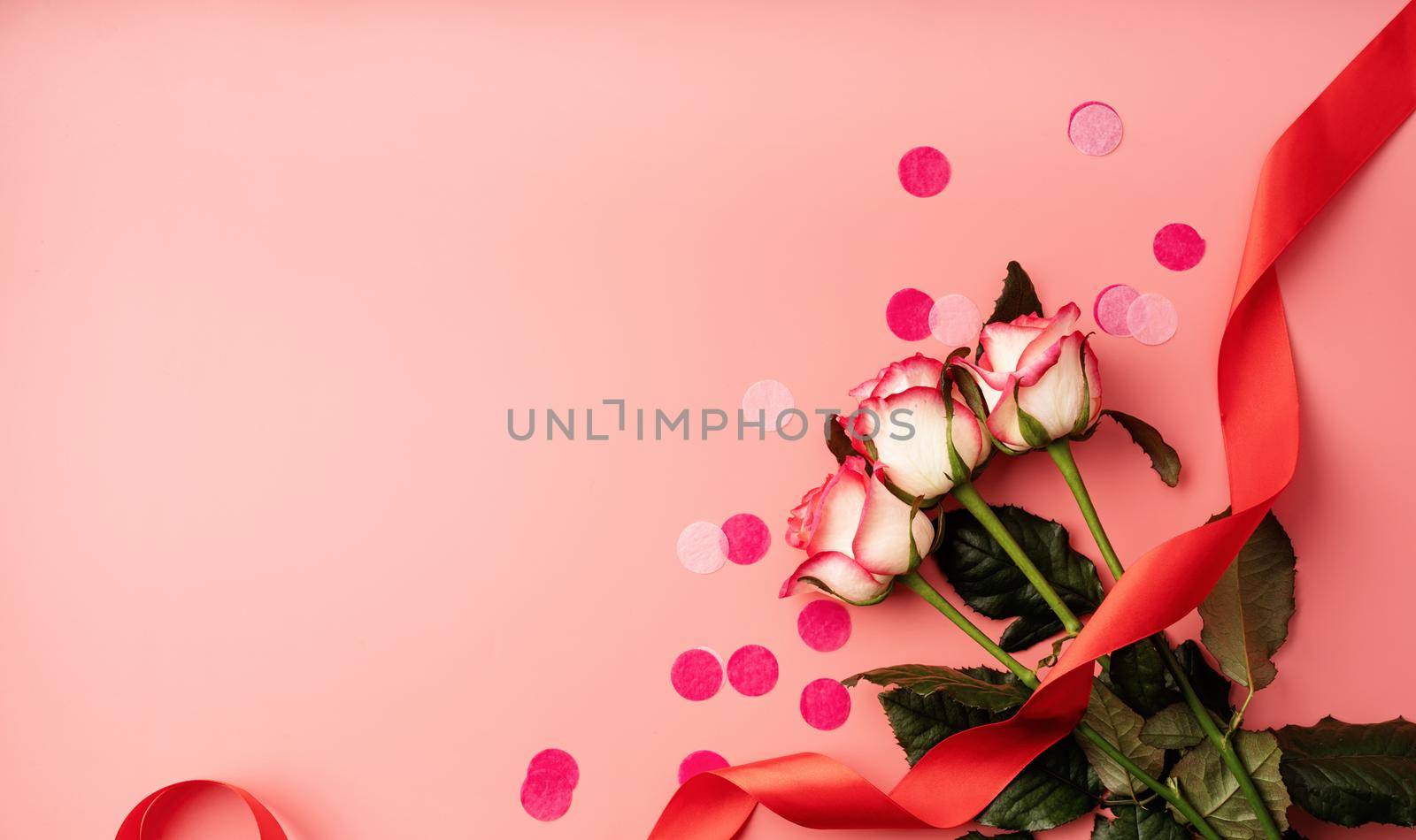 Valentines Day concept. Pink roses with confetti on solid pink background