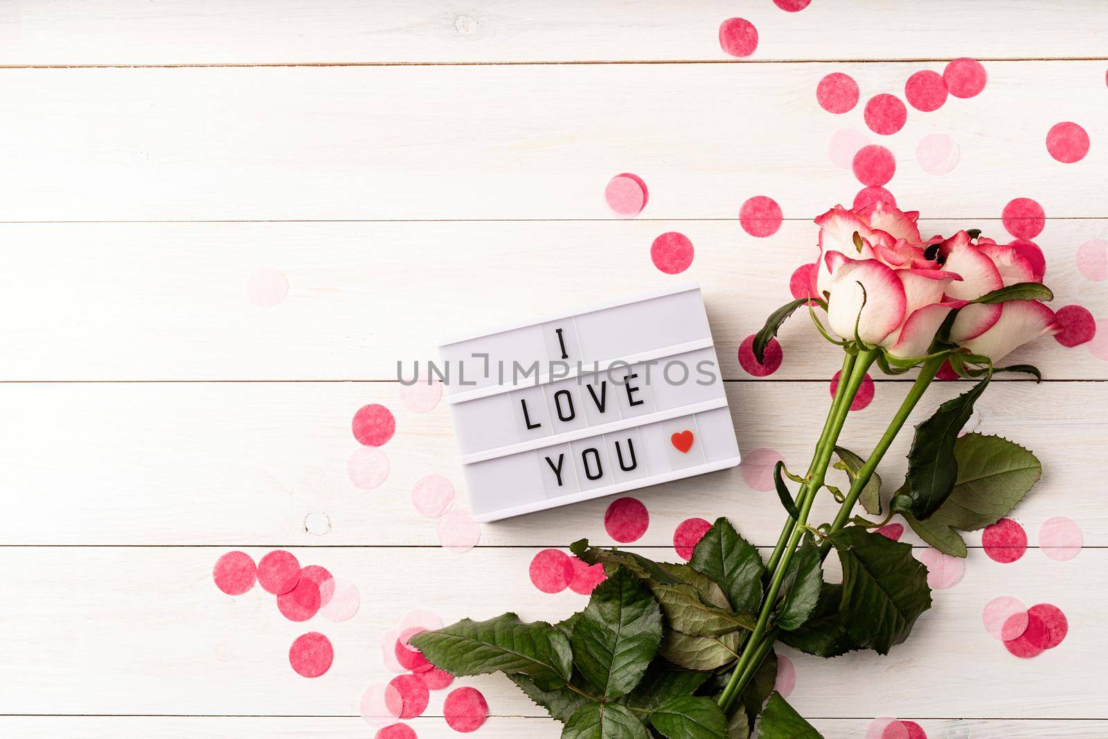 i love you words on a lightbox with pink roses top view flat lay on white background by Desperada