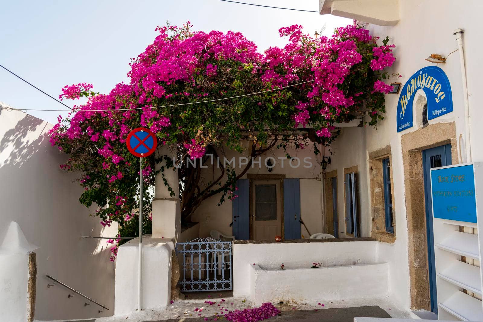 Kythira, Greece - August 26, 2021: Traditional house in the traditional settlement of Chora, the capital of Kythira island, Greece. Typical architecture of whitewashed house blue wooden door and red bougainvillea.