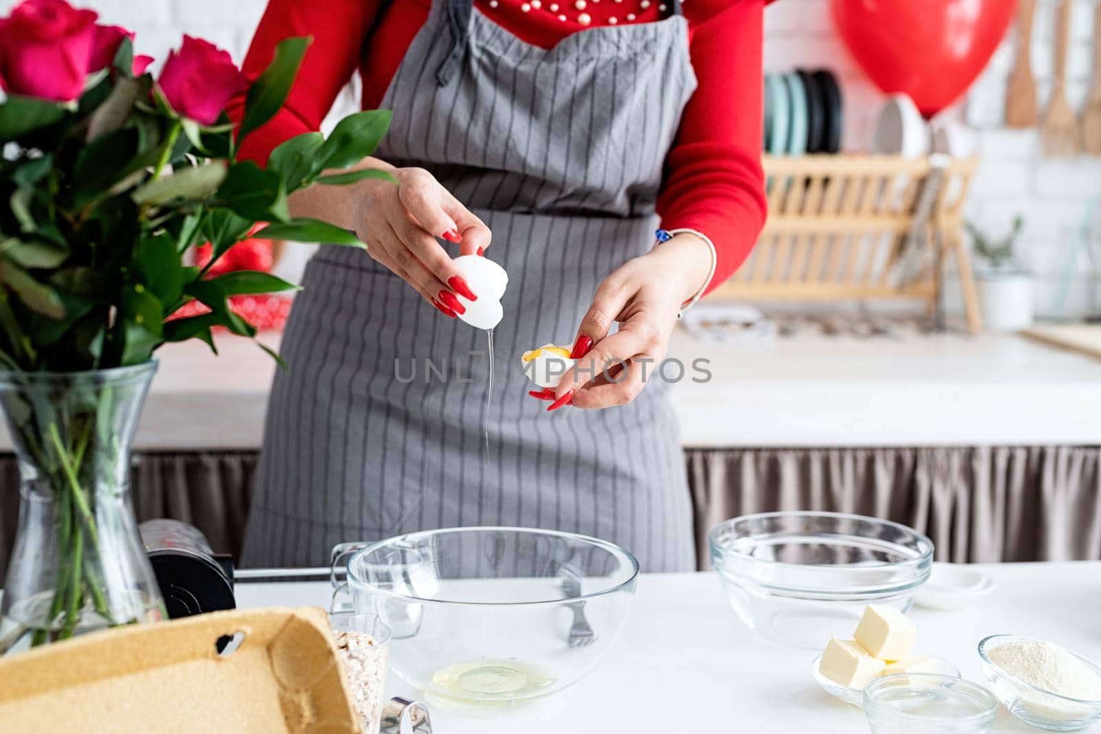 Woman in red dress and gray apron making valentine cooking at the kitchen by Desperada