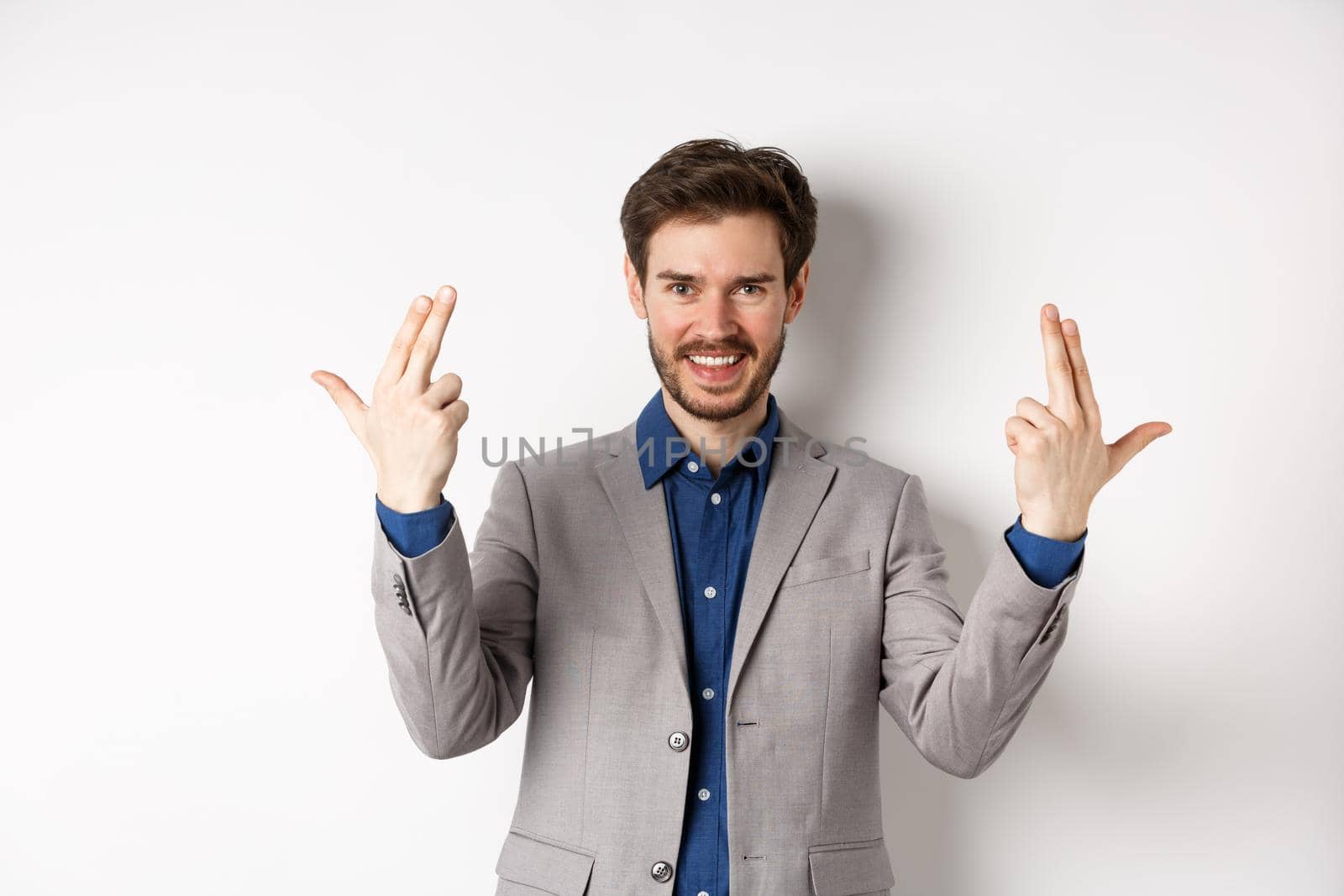 Excited successful businessman showing shot gun sign and smiling pleased, feel motivated and positive, standing in suit on white background by Benzoix