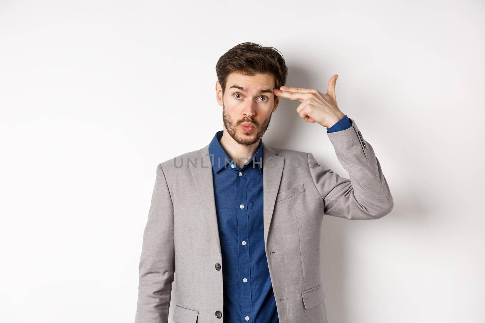 Annoyed guy in business suit shoot himself with hand gun near head, look distressed and tired after work, standing on white background by Benzoix