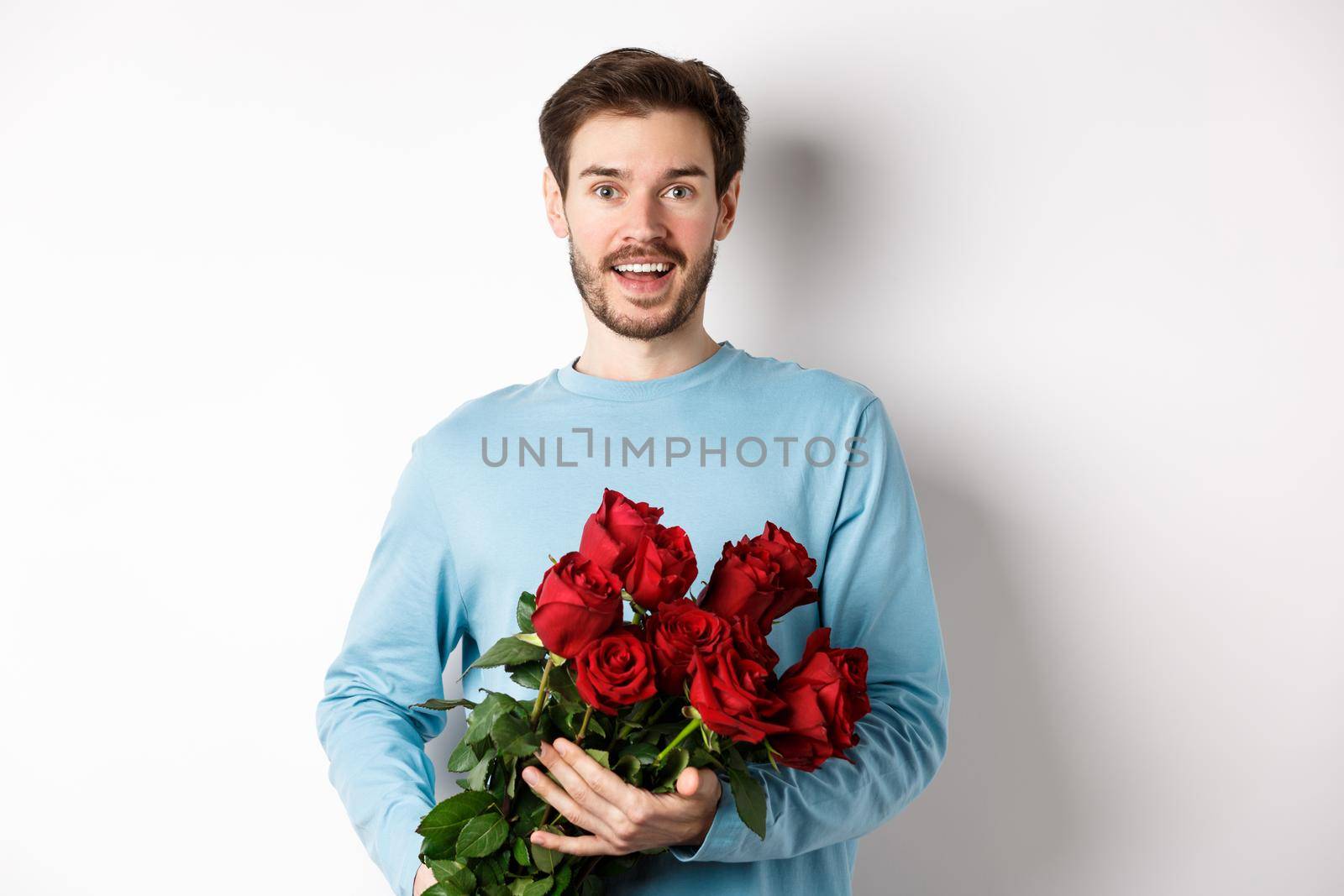 Romantic boyfriend bring beautiful bouquet of red roses on valentines day, having date with girlfriend, saying I love you, standing passionate on white background.