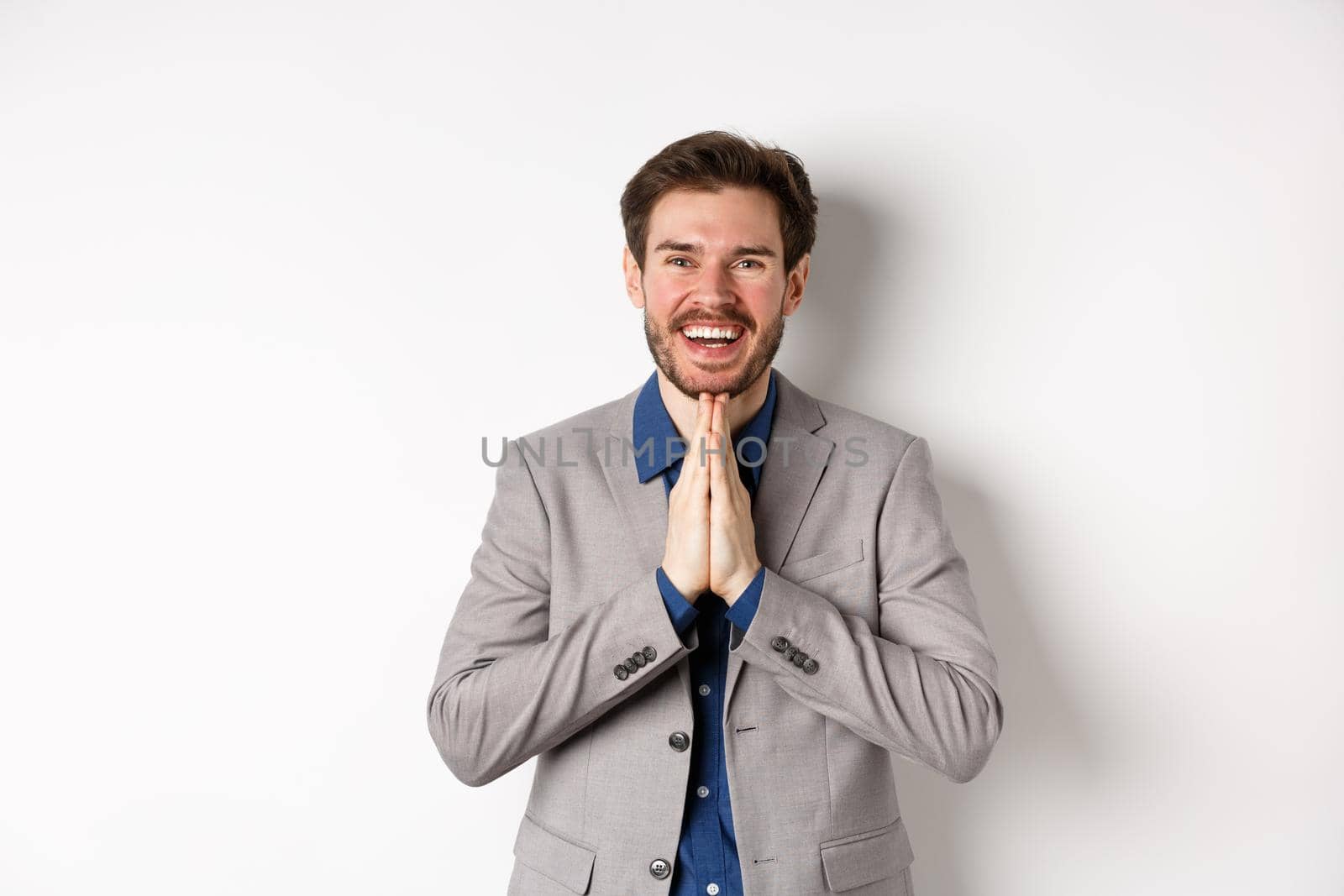 Happy caucasian businessman say thank you, smiling and laughing with hands showing namaste sign, express gratitude, standing on white background.