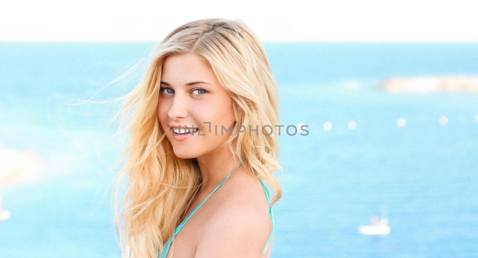 Beauty, wellness and summer portrait. Beautiful young woman with long blond hair, happy blonde smiling, blue sea on background.