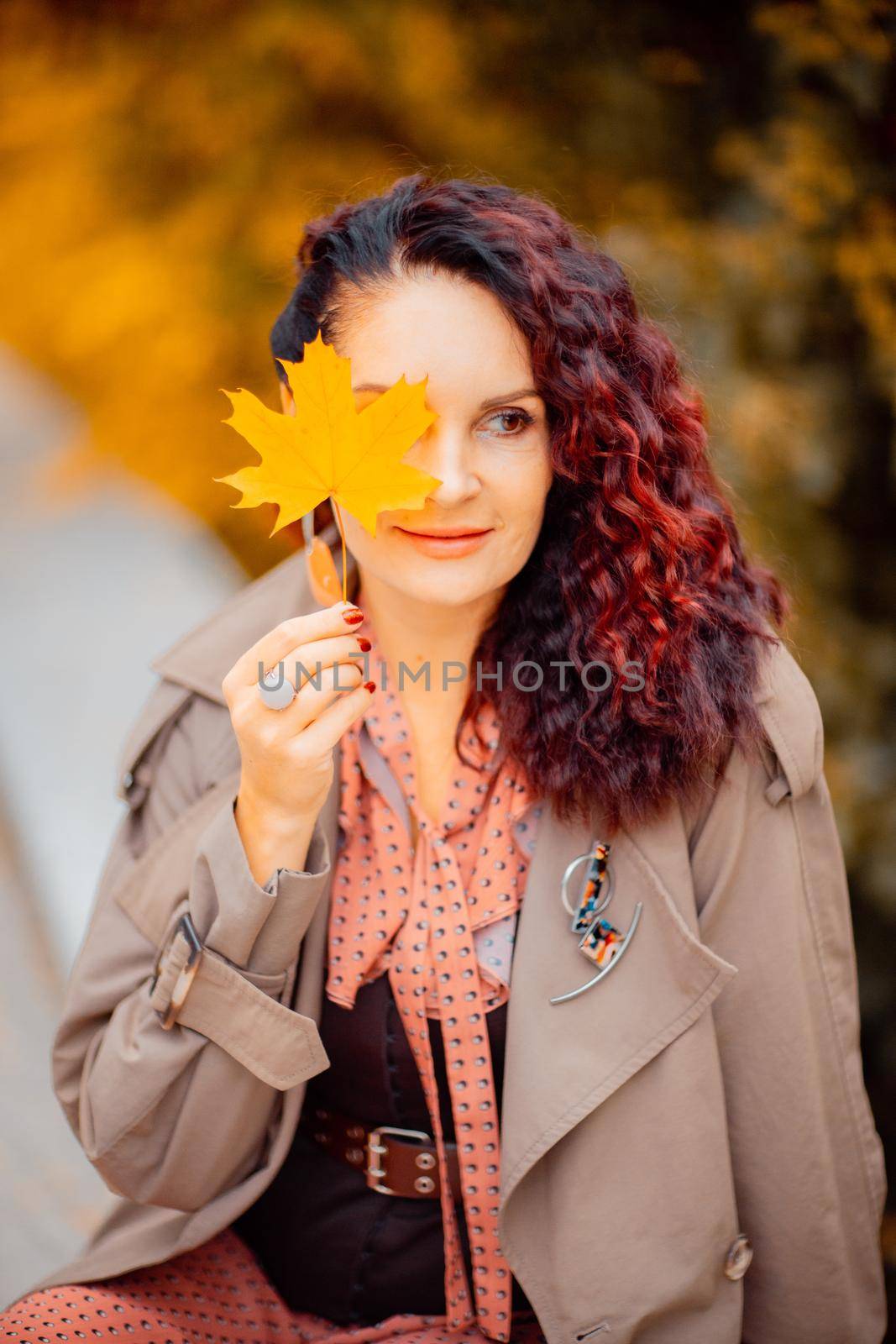 Beautiful girl walking outdoors in autumn. Smiling girl collects yellow leaves in autumn. Young woman enjoying autumn weather. by Matiunina