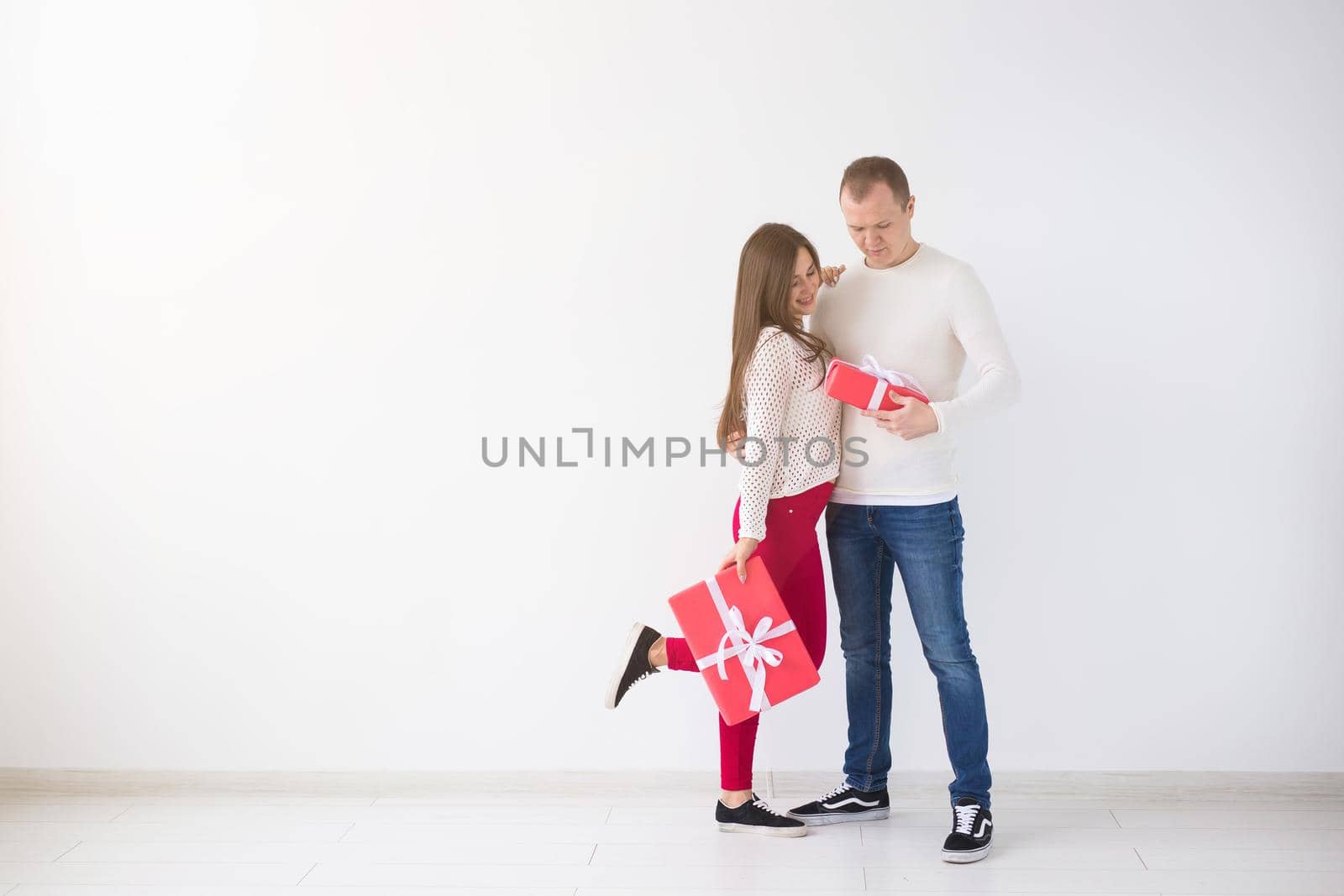 People, christmas, birthday, holidays and valentine's day concept - happy young man and woman with gift boxes on white background with copy space.