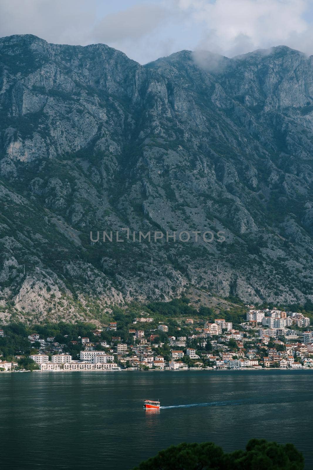 Boat sails along the bay against the backdrop of the old town at the foot of the mountains. High quality photo