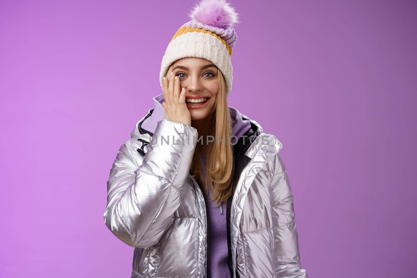 Delighted amused tender blond girlfriend fool around look playful playing snowballs touch cheek astonished feel dream come true enjoying vacation winter holidays boyfriend, standing purple background.