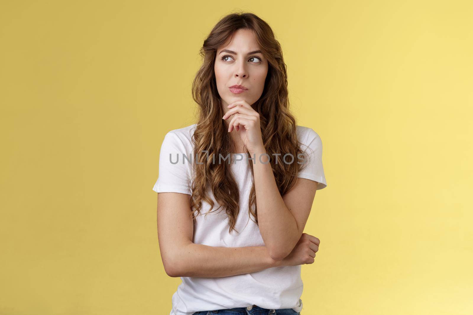 Thoughtful smart creative female freelancer trying solve puzzle making choice pondering decision touch chin thinking look away focused thinking deep stand yellow background by Benzoix