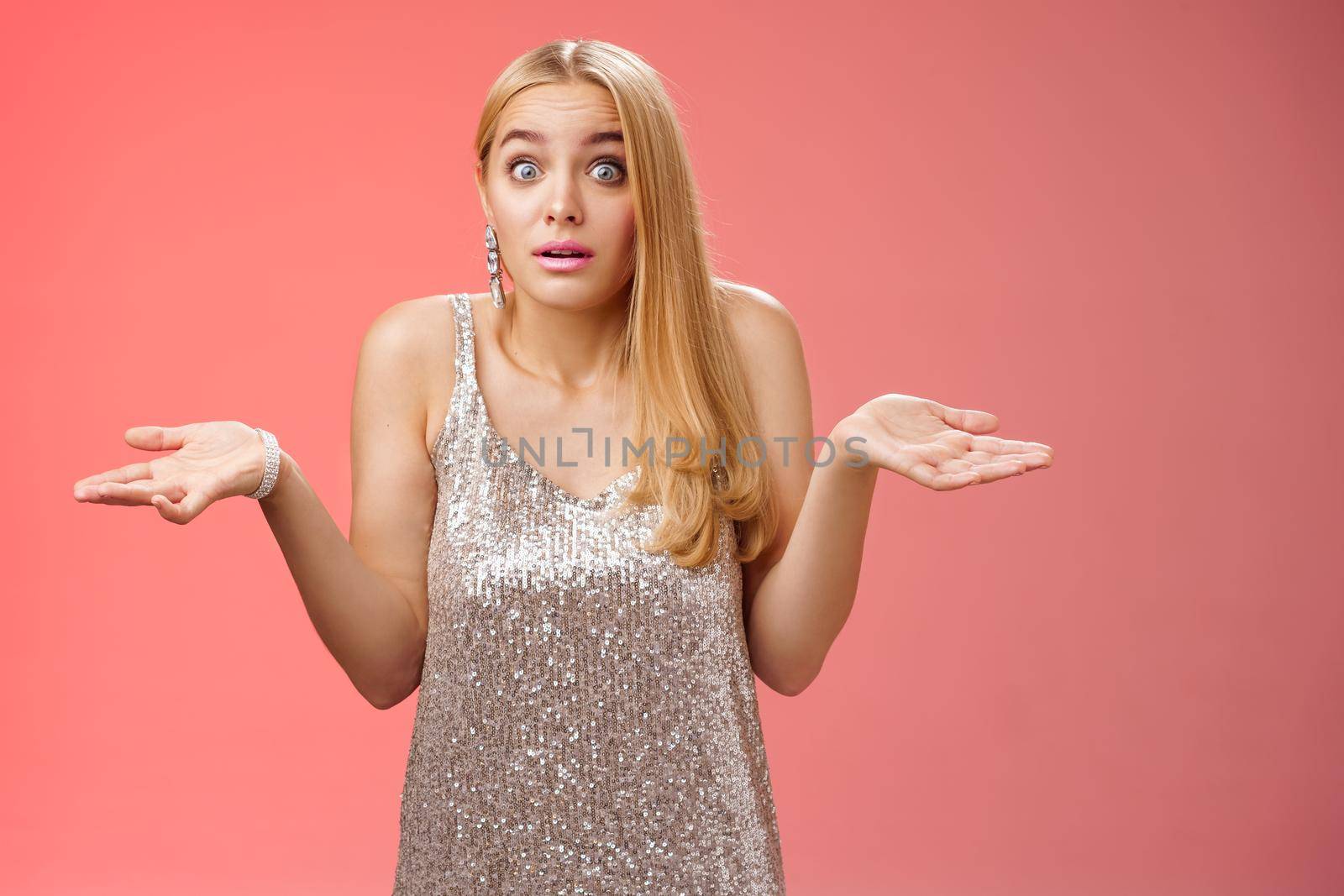 Unsure clueless awkward attractive blond european woman in silver glamour dress shrugging hands sideways widen eyes raise eyebrows unaware no idea what happening, standing questioned confused by Benzoix