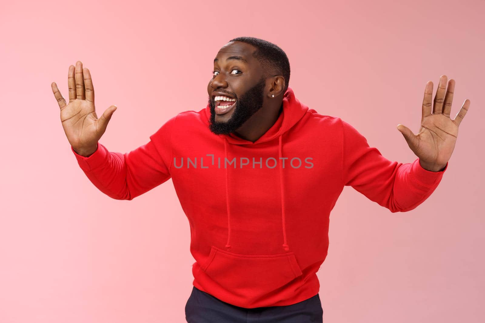 Knock who there. Charming happy funny black bearded guy bending towards camera raised palms move like mime act pressed face glass smiling joyfully fool around playful energized mood.