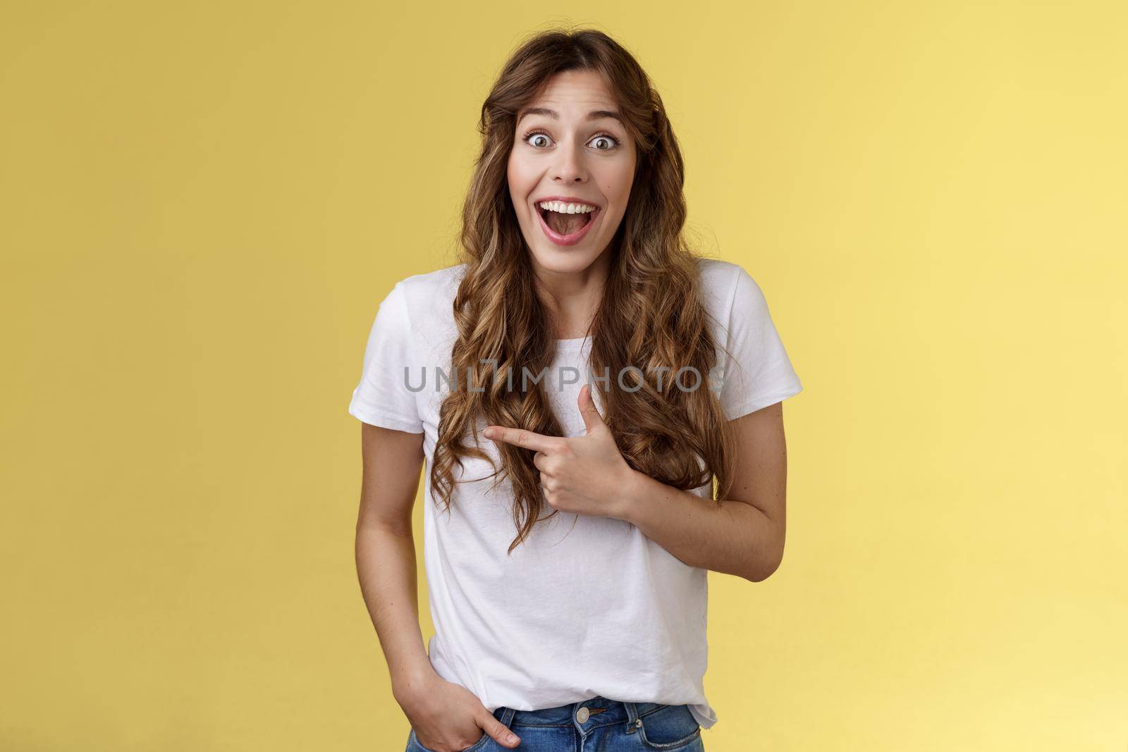 Joyful charismatic woman having fun chatting friend have funny amusing conversation discuss comedy movie pointing left fascinated impressed open mouth smiling broadly laughing yellow background by Benzoix