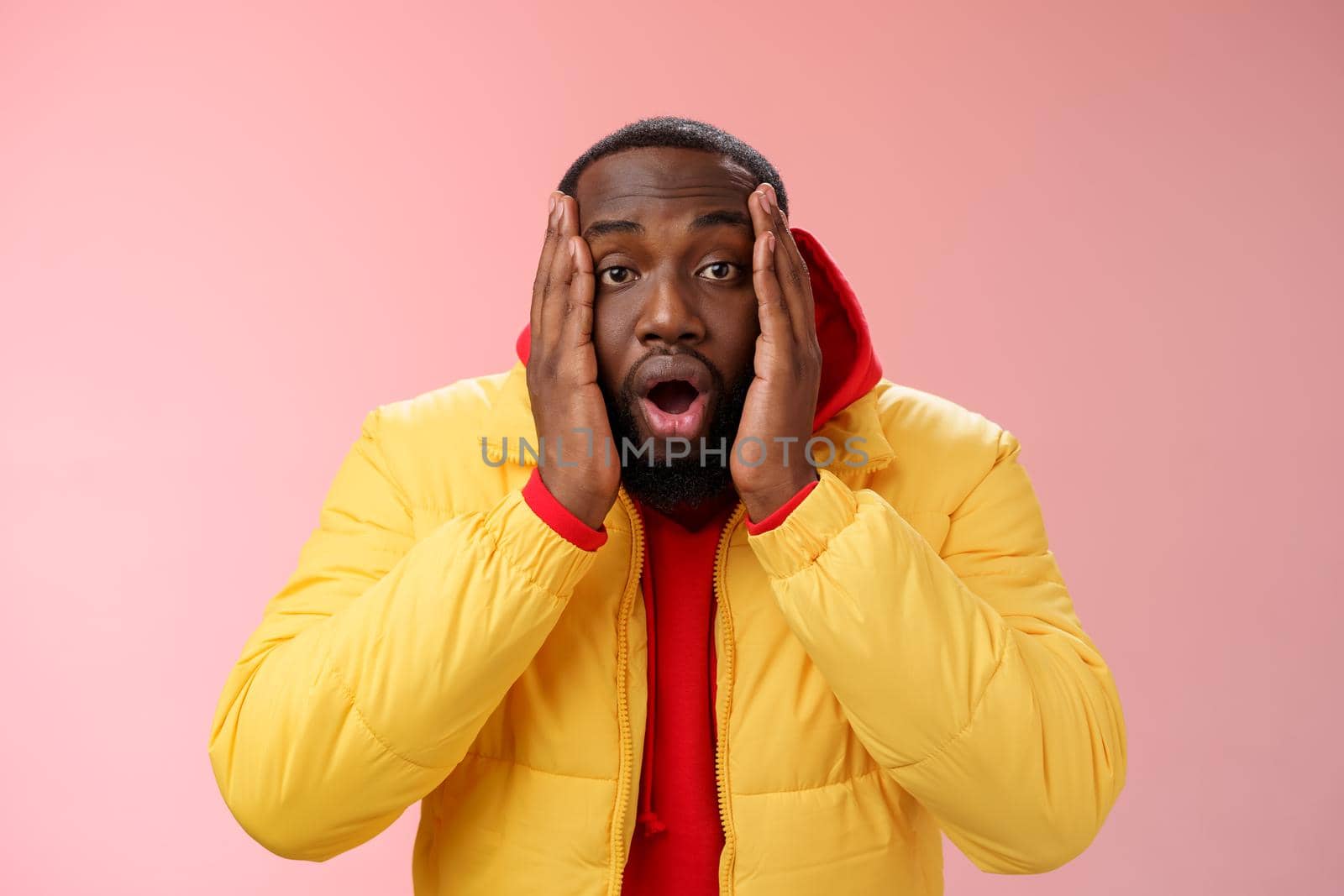 Shocked amazed impressed handsome african bearded guy drop jaw gasping astonished press palms cheeks witness surprising unexpected event, standing speechless stupor pink background. Copy space