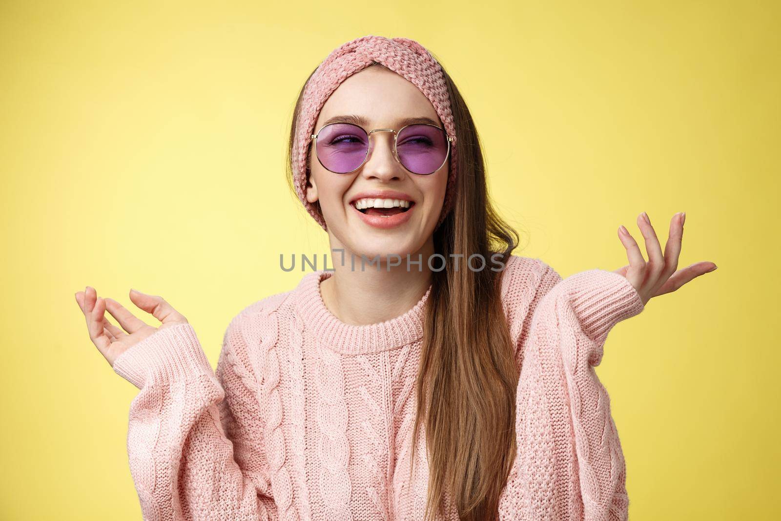 Cute glamour satisfied carefree female tourist getting ready sea vacation wearing trendy sunglasses spread hands sideways looking aside smiling delighted, enjoying vacation over yellow background.
