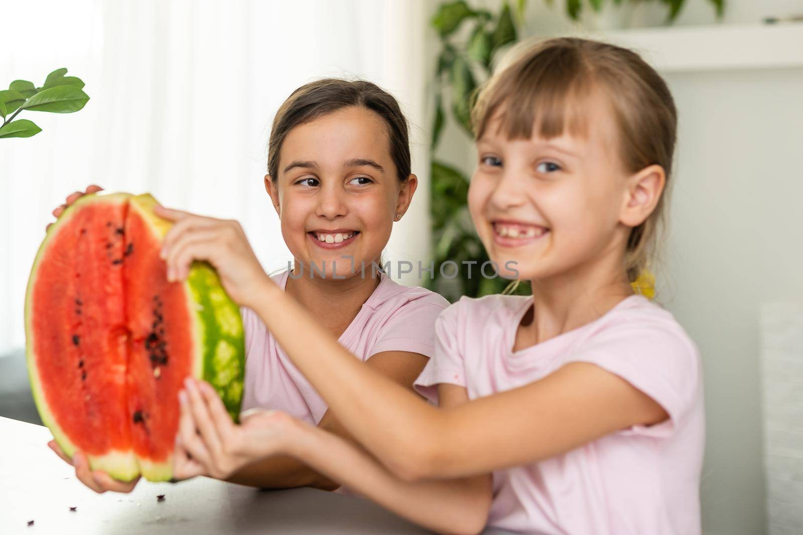 Two kids eating one slice of watermelon. Kids eat fruit outdoors. Healthy snack for children