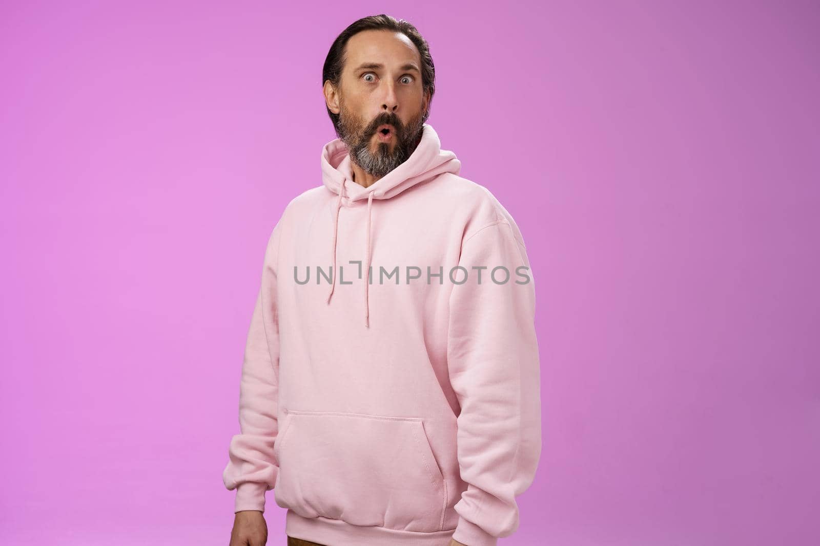 Impressed speechless shocked adult bearded man grey hair in cool pink hoodie folding lips wow popping eyes camera surprised astonished intrigued, standing curious amazed purple background by Benzoix