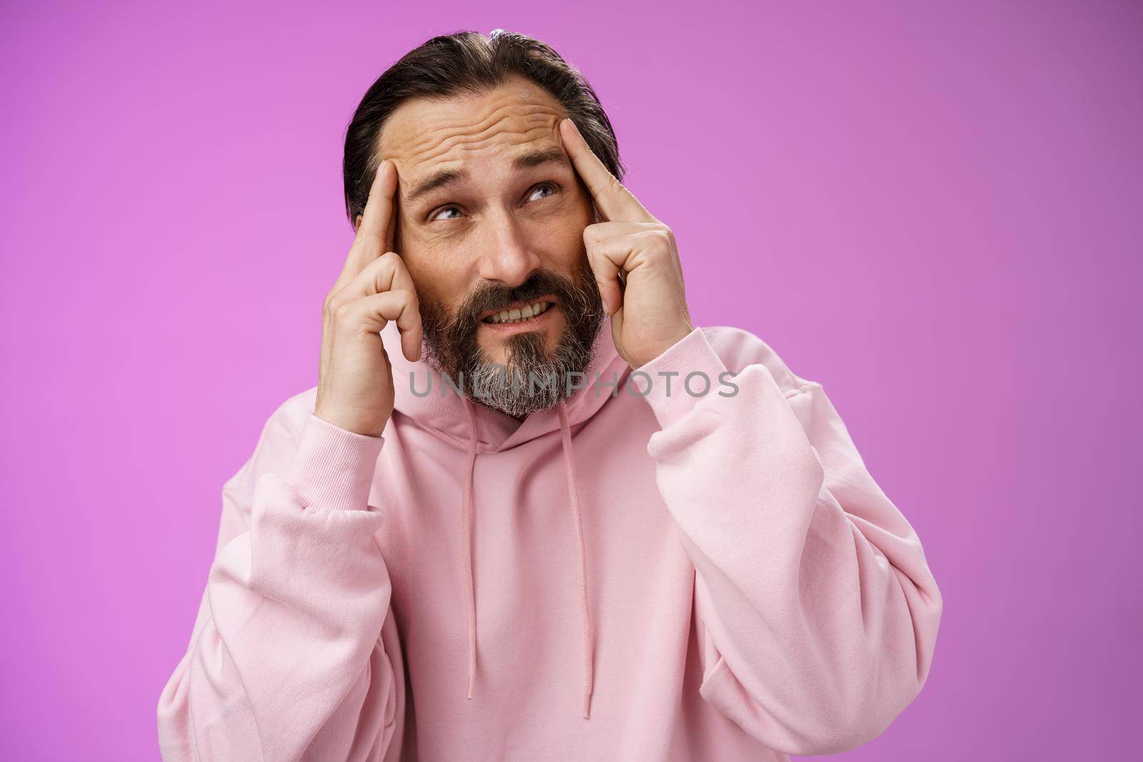 Worried intense disturbed mature male writer cannot create idea standing pressured touch forehead frowning look up problem concentrate not focused, standing purple background upset distracted by Benzoix