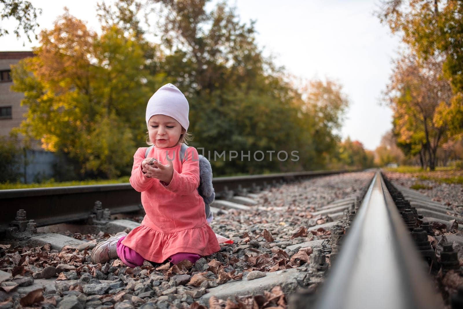 portrait of little girl plays on railroad autumn day