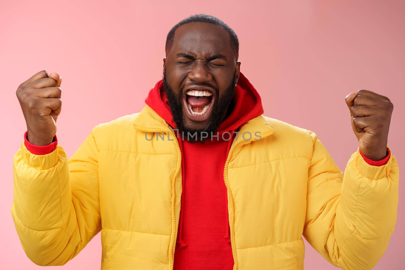 Handsome african-american man encouraging himself put will effort clenched arms yelling close eyes raise hands boost confidence, standing pink background express rage release emotions.