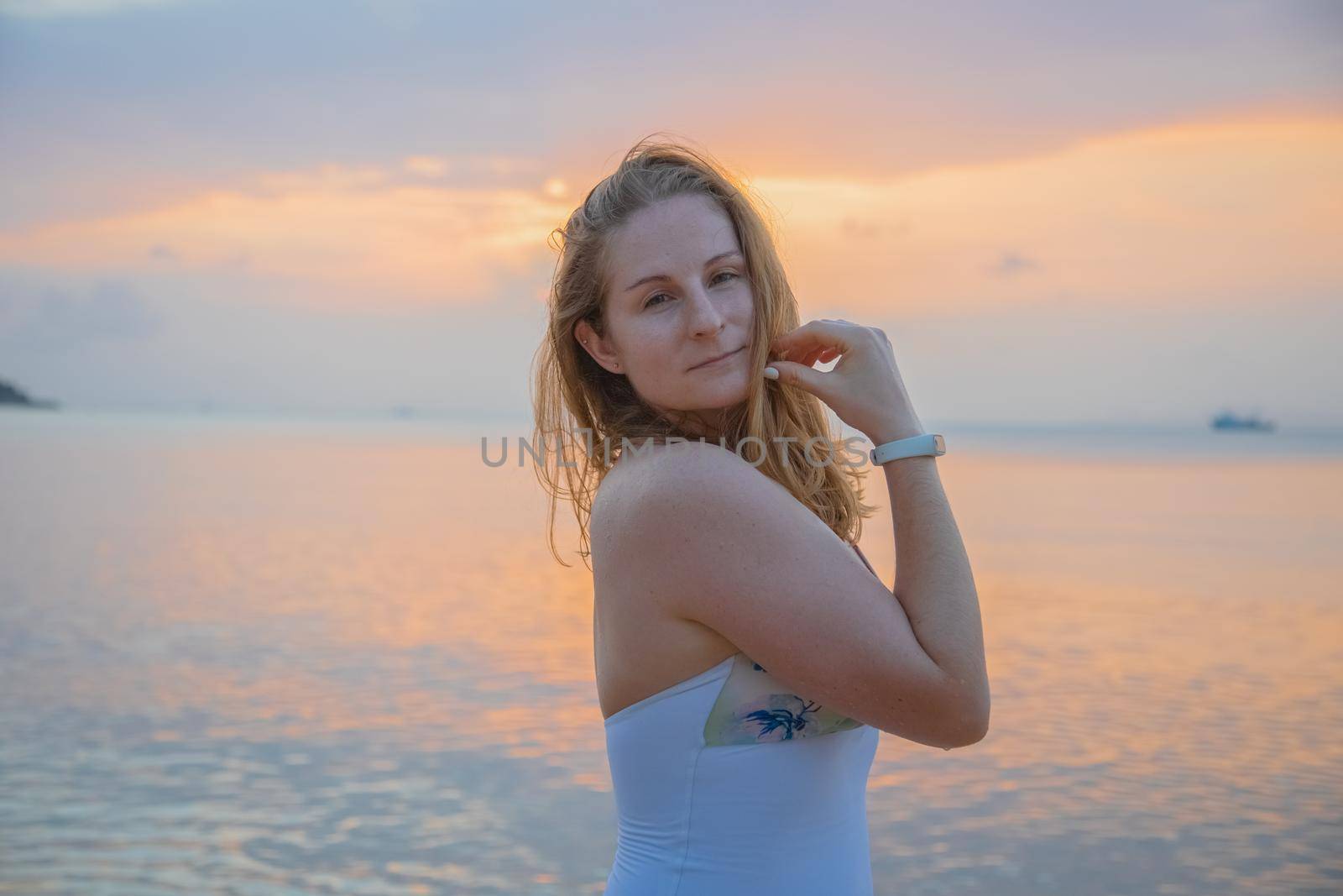 portrait of beautiful young woman on the background of sunset by the sea