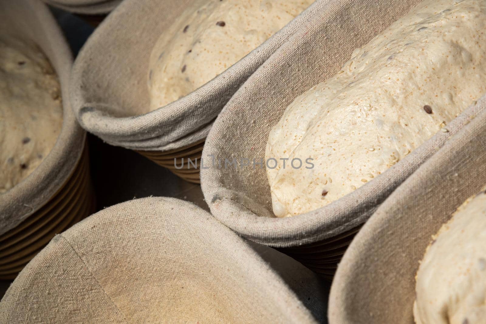 Close-up Raw wholemeal cereal bread dough in a dish lined with baking cloth. Craft bakery. Healthy and wholesome food.