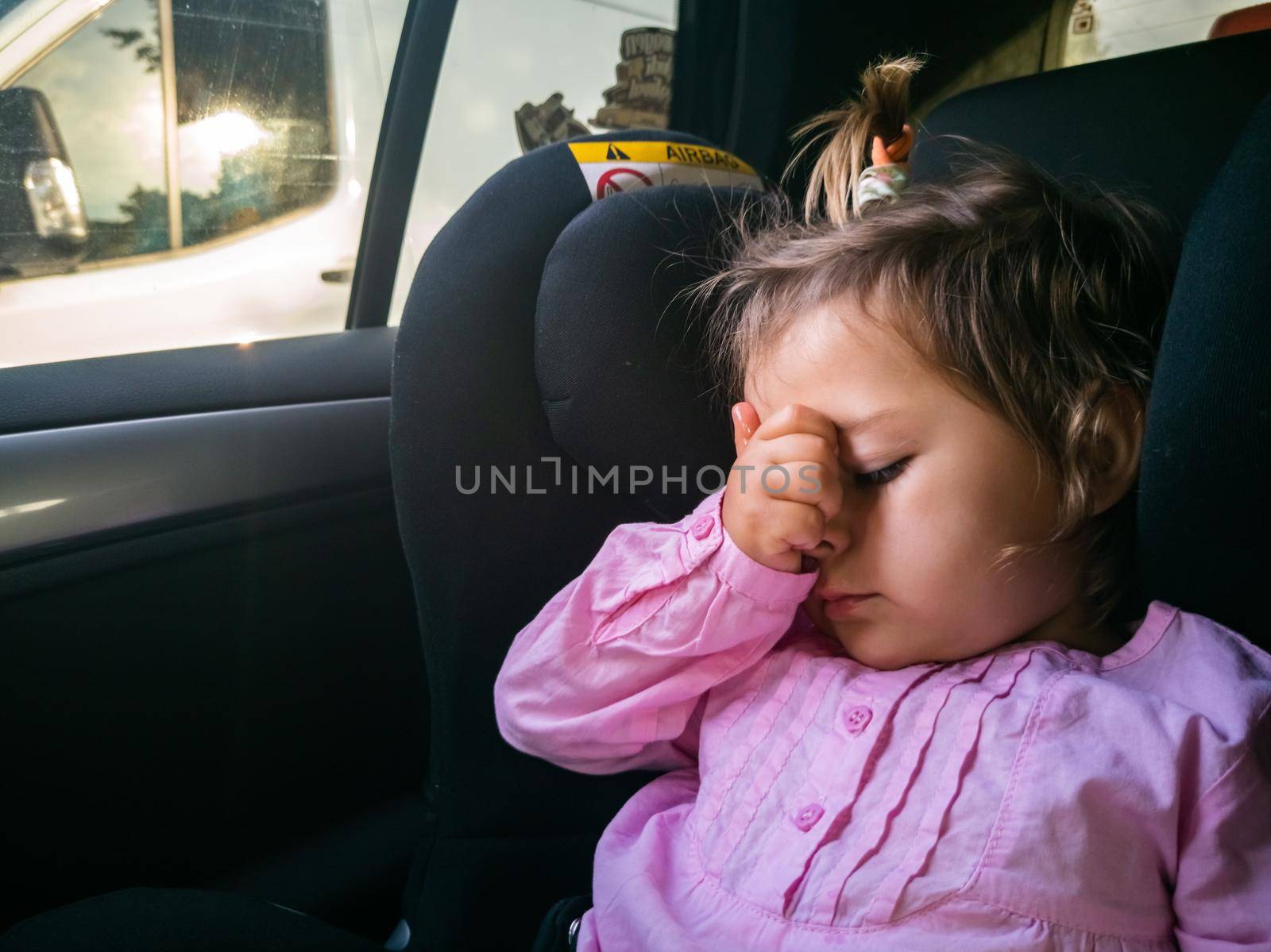 the child was seasick in the car. sad toddler sitting in a child seat by Mariaprovector