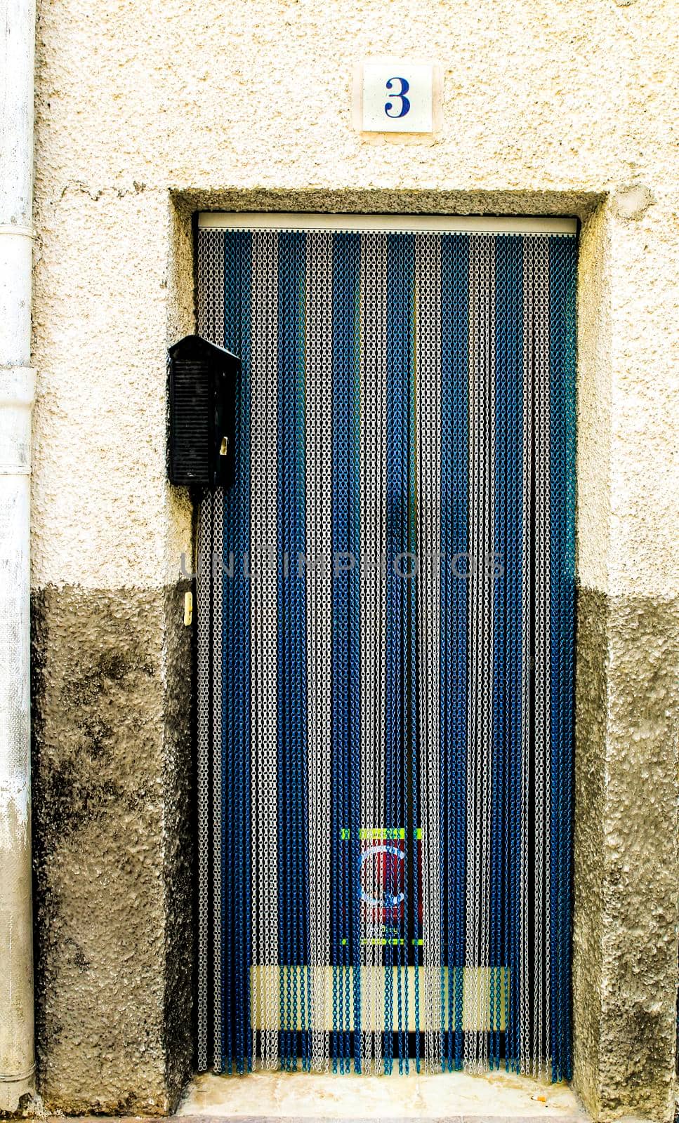 Beniarda, Alicante, Spain- November 26, 2021:Blue and white Striped metal curtain on door in Beniarda village, Alicante, Spain