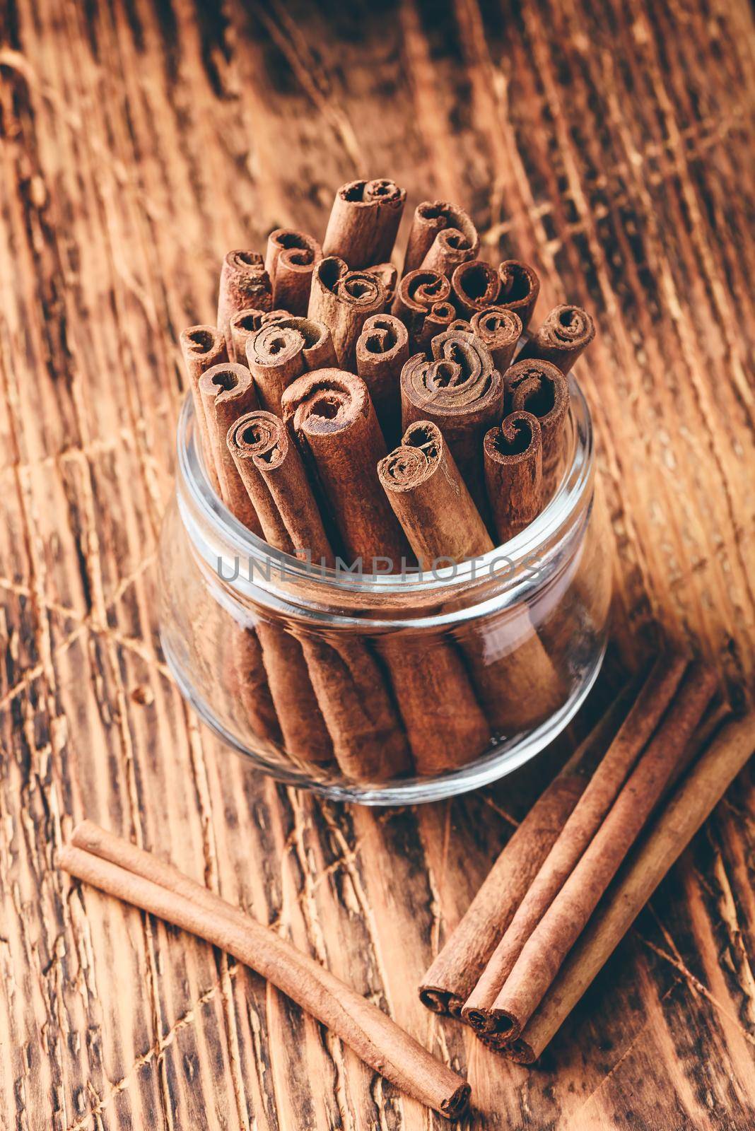 Cinnamon sticks in a glass jar over rustic wooden surface