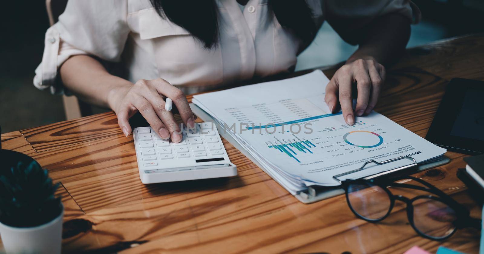 businesswoman working on desk with calculator with financial chart report in office. concept accounting finance. by nateemee