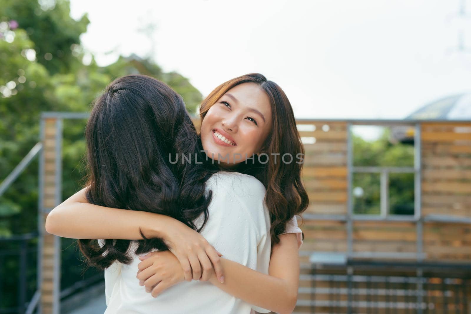 Beauties in style. Two beautiful young well-dressed women smiling at camera while standing embracing outdoors