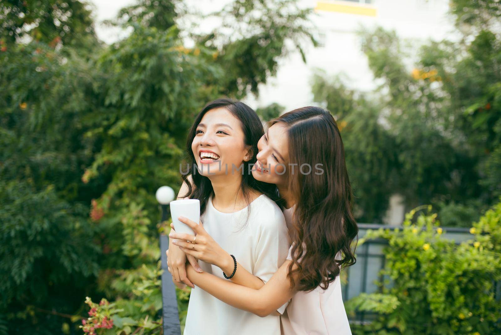 Two Women Relaxing On Rooftop Garden Drinking Coffee