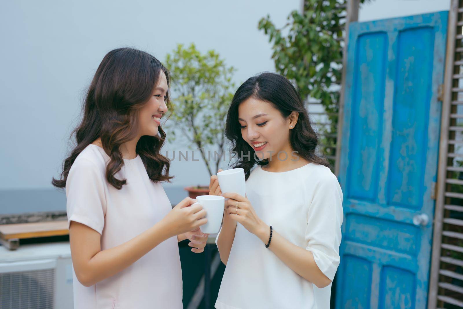 Two beautiful young well-dressed women chatting outdoors over coffee