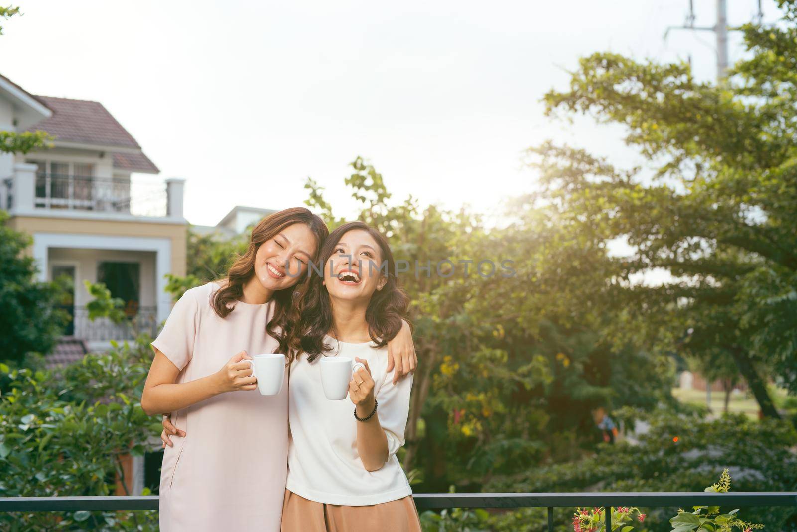 Two Women Relaxing On Rooftop Garden Drinking Coffee by makidotvn