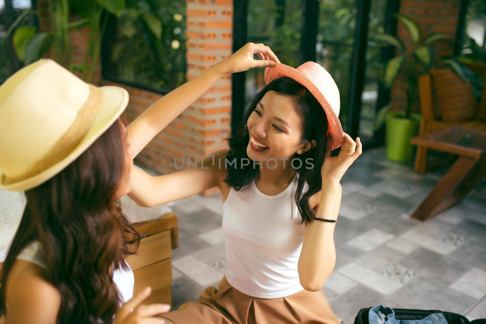 Two happy young women while packing suitcases at home for vacation or trip